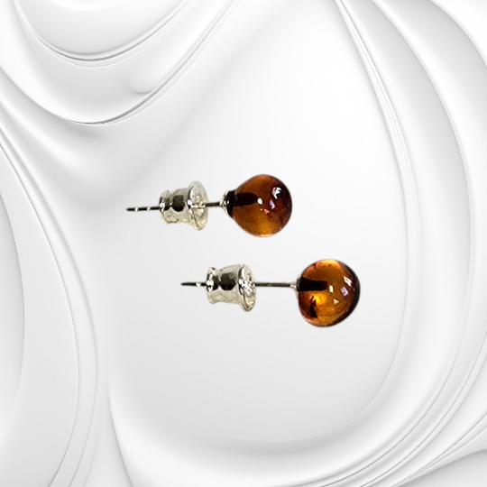 Srebrne kolczyki sztyfty z kulką bursztynu w odcieniu koniaku prezentujące elegancką i minimalistyczną formę.